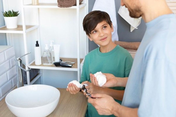 father teaching his son to wash hands